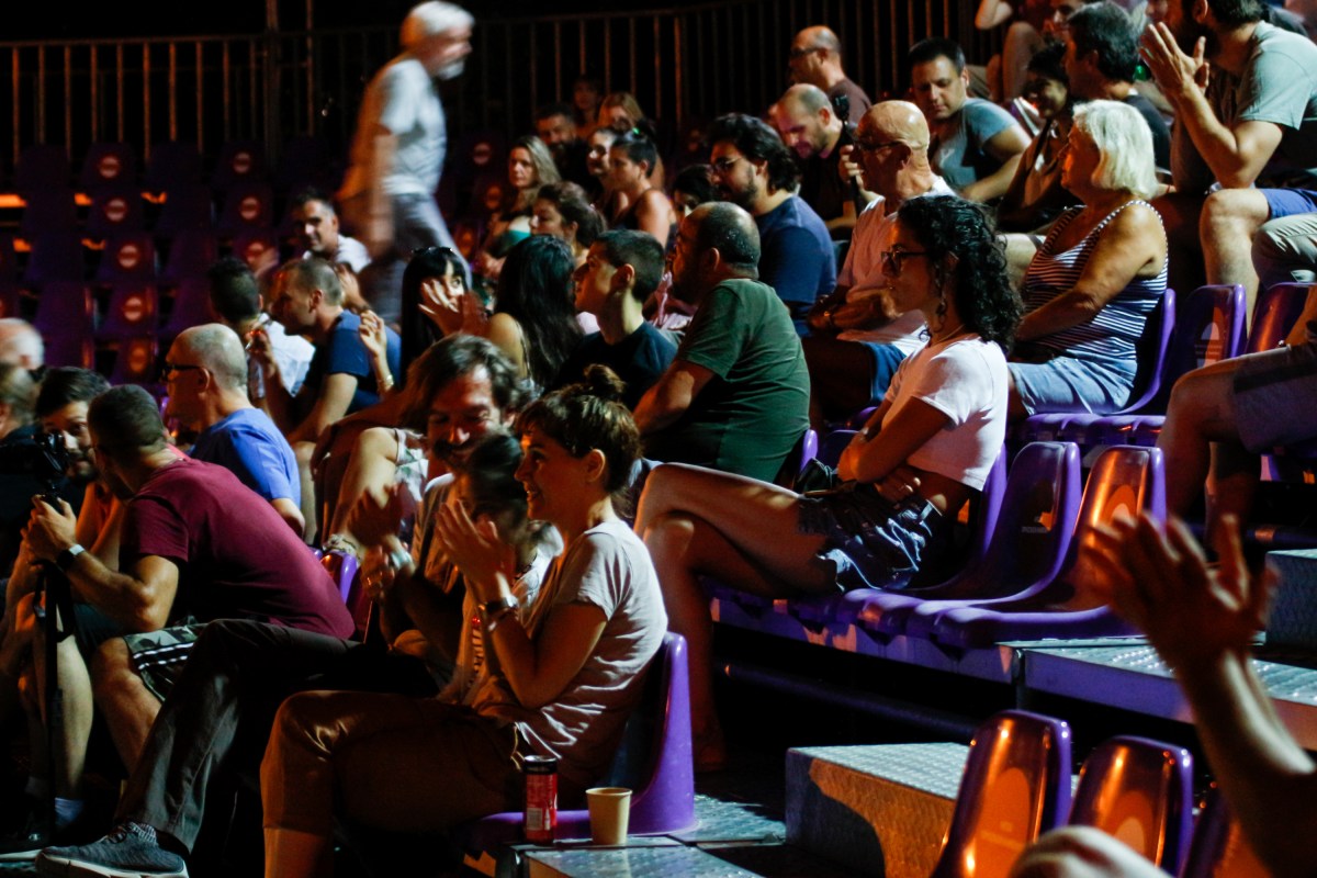 Το κοινό του Our Festival 5 κάθεται στα μωβ καθίσματα του Θεάτρου της Ρεματιάς περιμένοντας να αρχίσει η επόμενη δράση. Κάποιοι συζητούν, κάποιοι χειροκροτούν και άλλοι κοιτούν προς τη σκηνή.