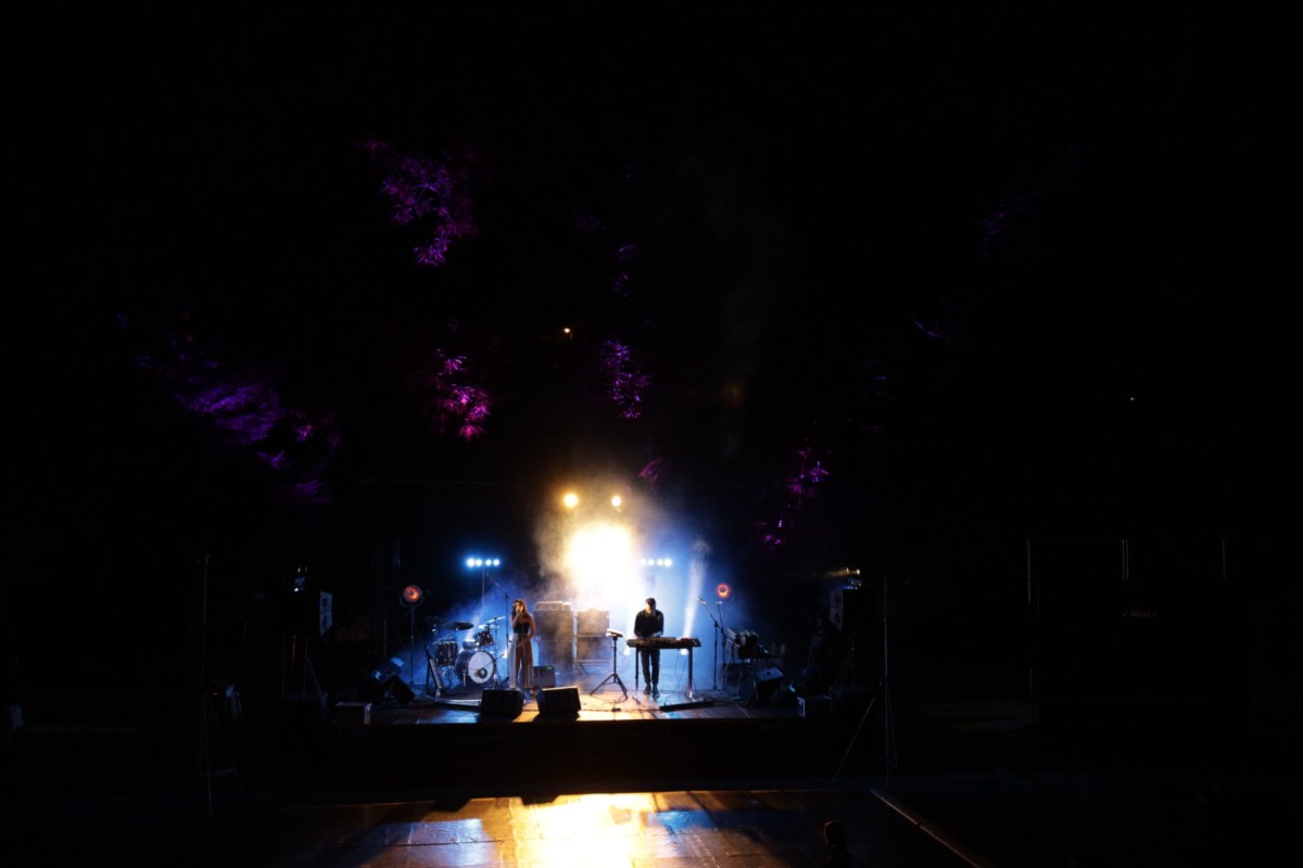 Στο σκοτεινό τοπίο του θεάτρου της Ρεματίας ξεχωρίζει η φωτισμένη σκηνή όπου μία κοπέλα με μαύρο τοπ και μπεζ παντελόνα τραγουδά και ένας νεαρός με τσουλούφι και μαύρα ρούχα παίζει ηλεκτρικό πιάνο. Το φως της σκηνής στέλνει τις ακτίνες του πάνω στα δέντρα που την περιβάλλουν.