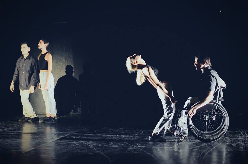 Στη μαύρη σκηνή του θεάτρου της Ρεματίας ένας άντρας με ατροφικά πόδια και μία γυναίκα με καστανά μαλλιά στέκουν όρθιοι αριστερά ενώ δεξιά μία ξανθιά γυναίκα κάμπτει τον κορμό της πίσω μπροστά από έναν άντρα σε αμαξίδιο.